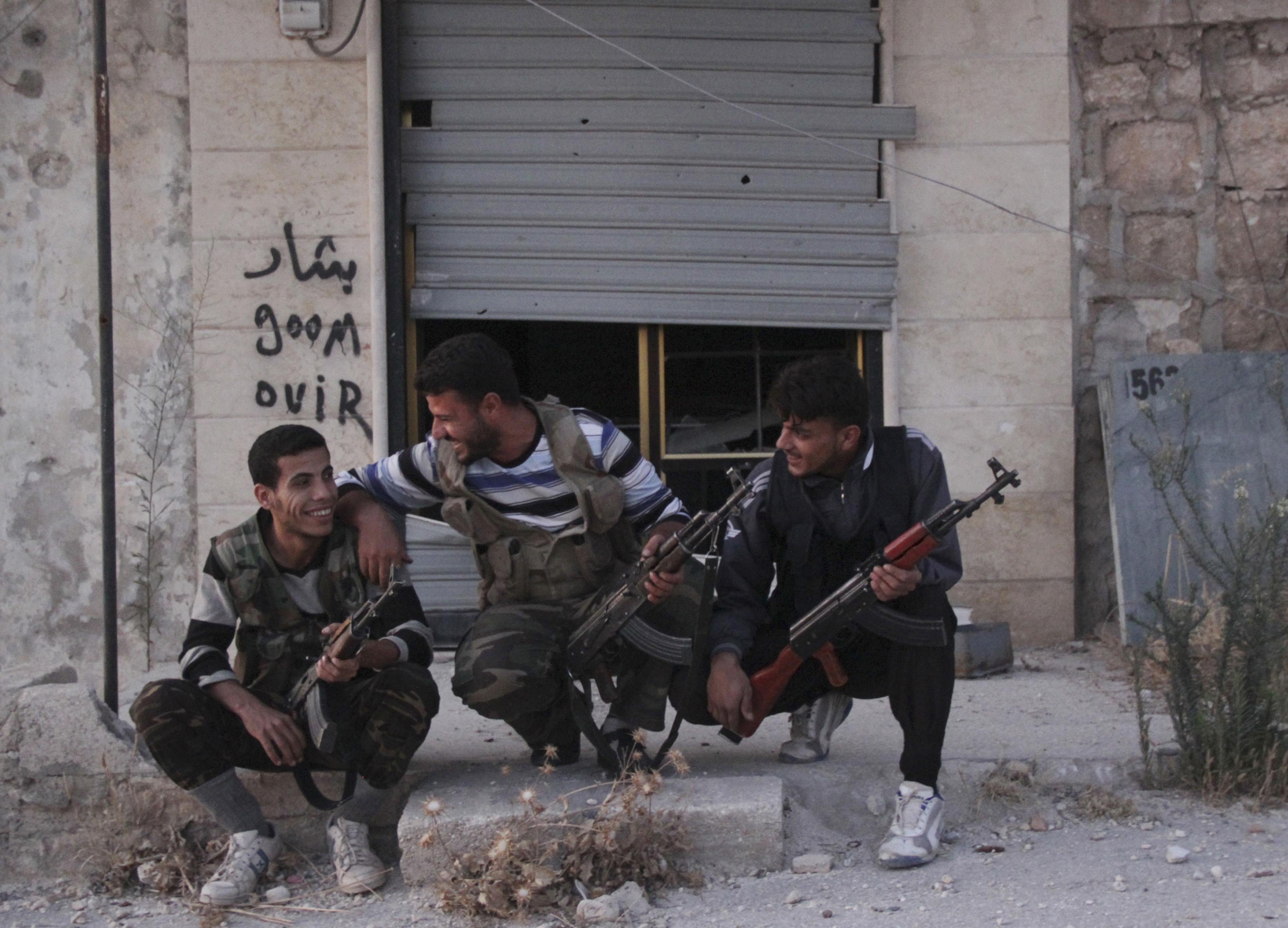 Free Syrian Army fighters react as they sit together along a street in Kansafra in Idlib province