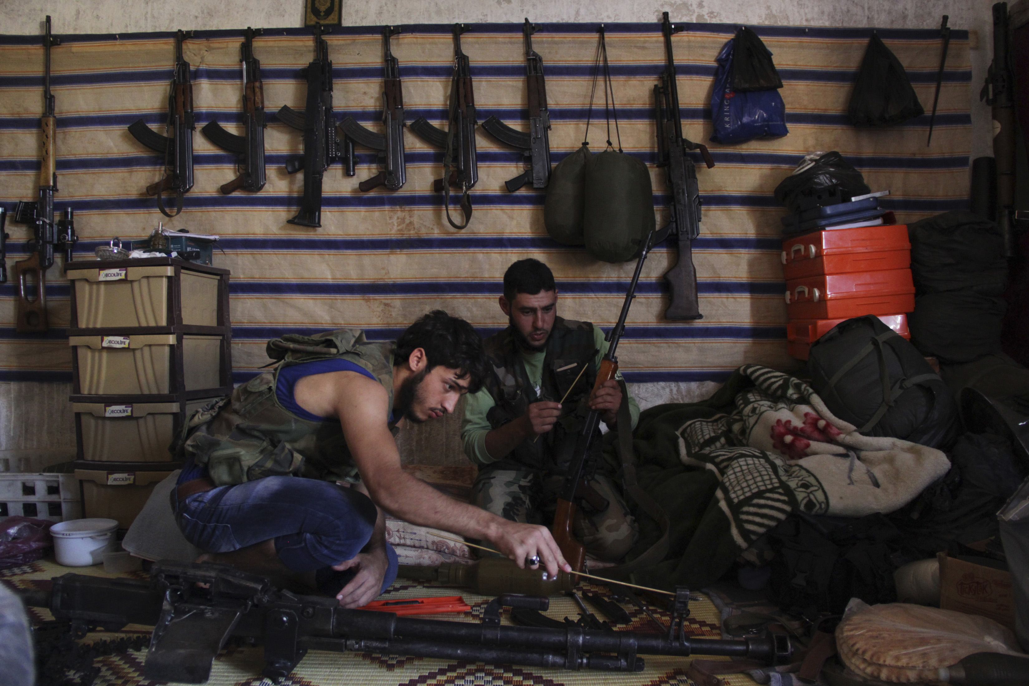 Free Syrian Army fighters sit inside a weapons warehouse in Kansafra