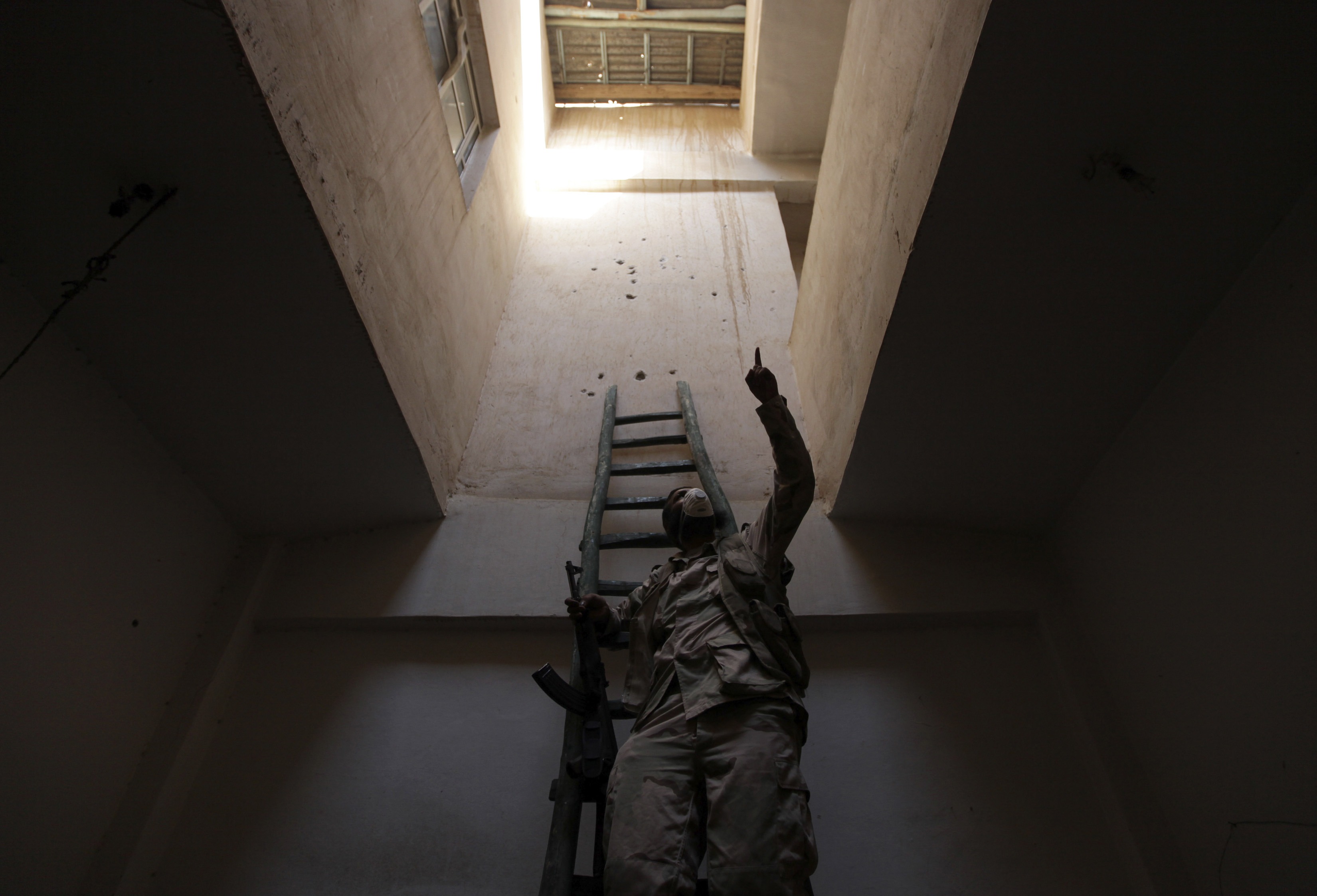 A Free Syrian Army fighter gestures as he climbs a ladder inside a building in Deir al-Zor